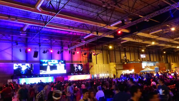 Counter-Strike tournament final in a large hall, big screens above the stage and a crowd watching from behind