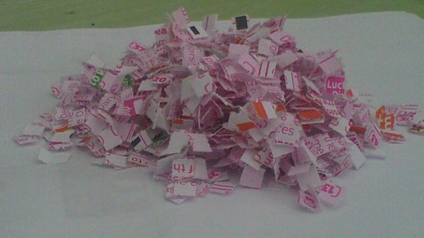 A pile of shredded lottery tickets on a white sheet of paper